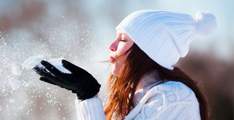 Bild einer Frau die den Schnee in Ihrer Hand wegbläst.
